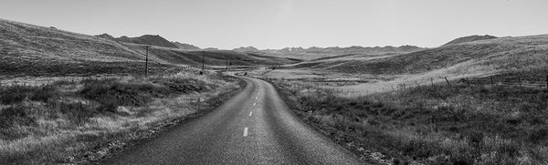 Black and white fine art photography print of a winding road through rolling hills near Wanaka New Zealand with distant mountain ranges