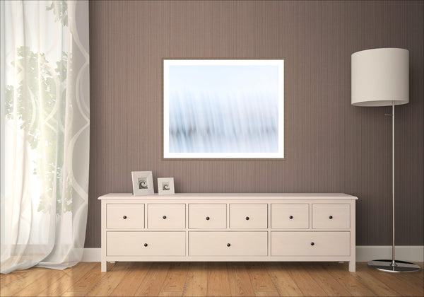 Echoes of Light, abstract Intentional Camera Movement fine art print, pale blue and white tones with soft vertical streaks, framed in a dark timber frame in a room mockup