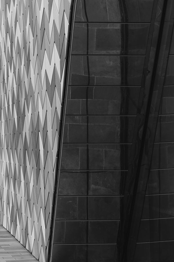 Black and white fine art photography print of geometric chevron tile facade contrasting with dark reflective glass in Christchurch New Zealand